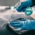 Person Cleaning Counter with Gloves and Disinfectant