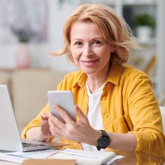 Woman smiling using phone and laptop